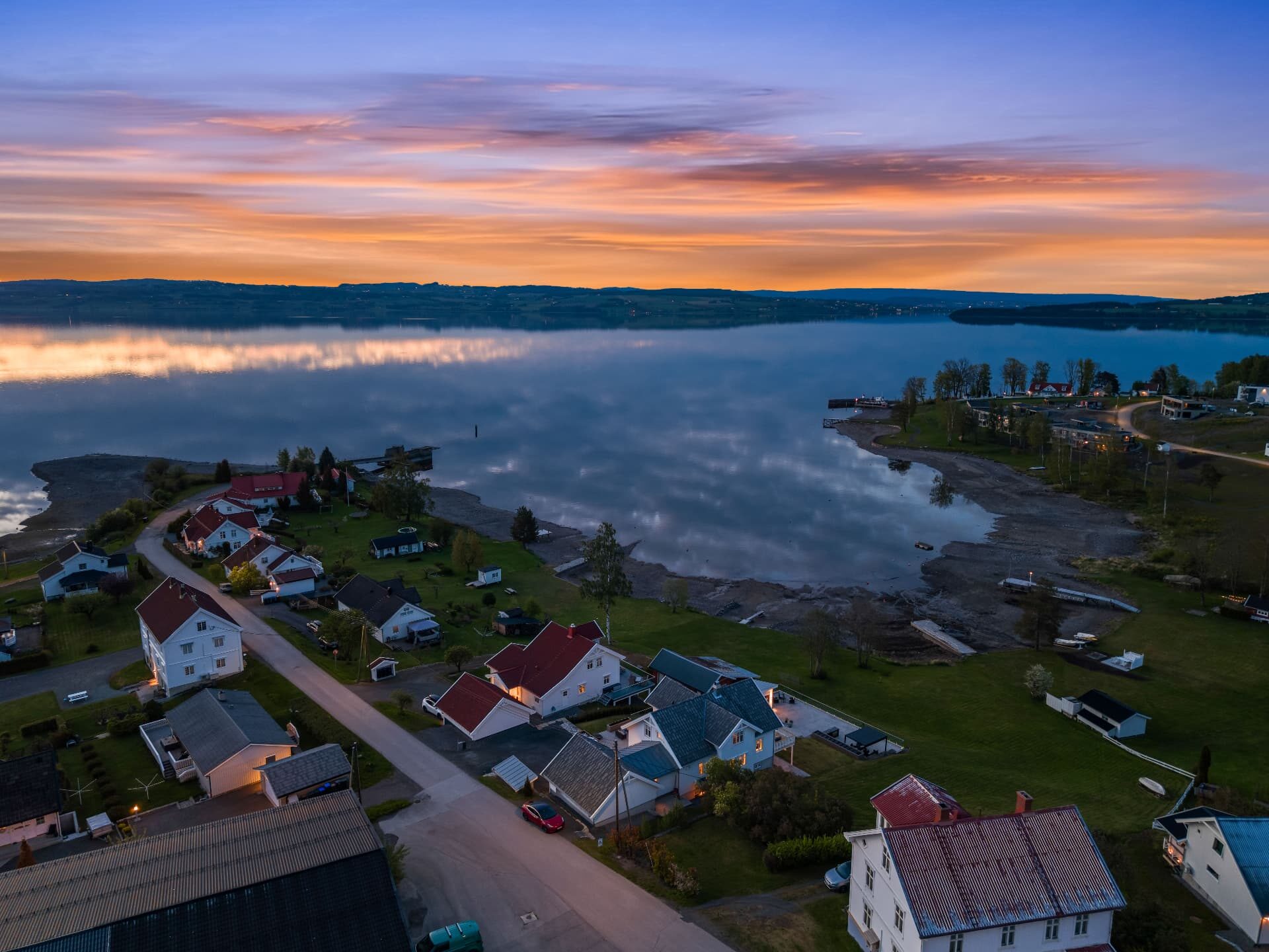 Luftfoto over boligområde og Mjøsa i solnedgang